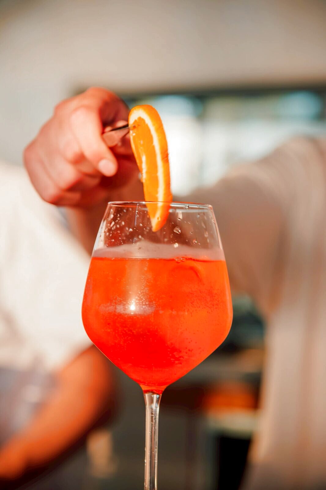 Hand garnishing an orange spritz with a twist of orange peel