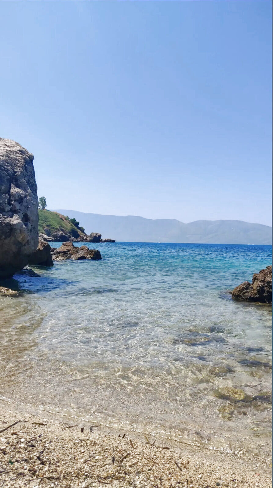 Clear shallow water in a rocky cove framed by boulders